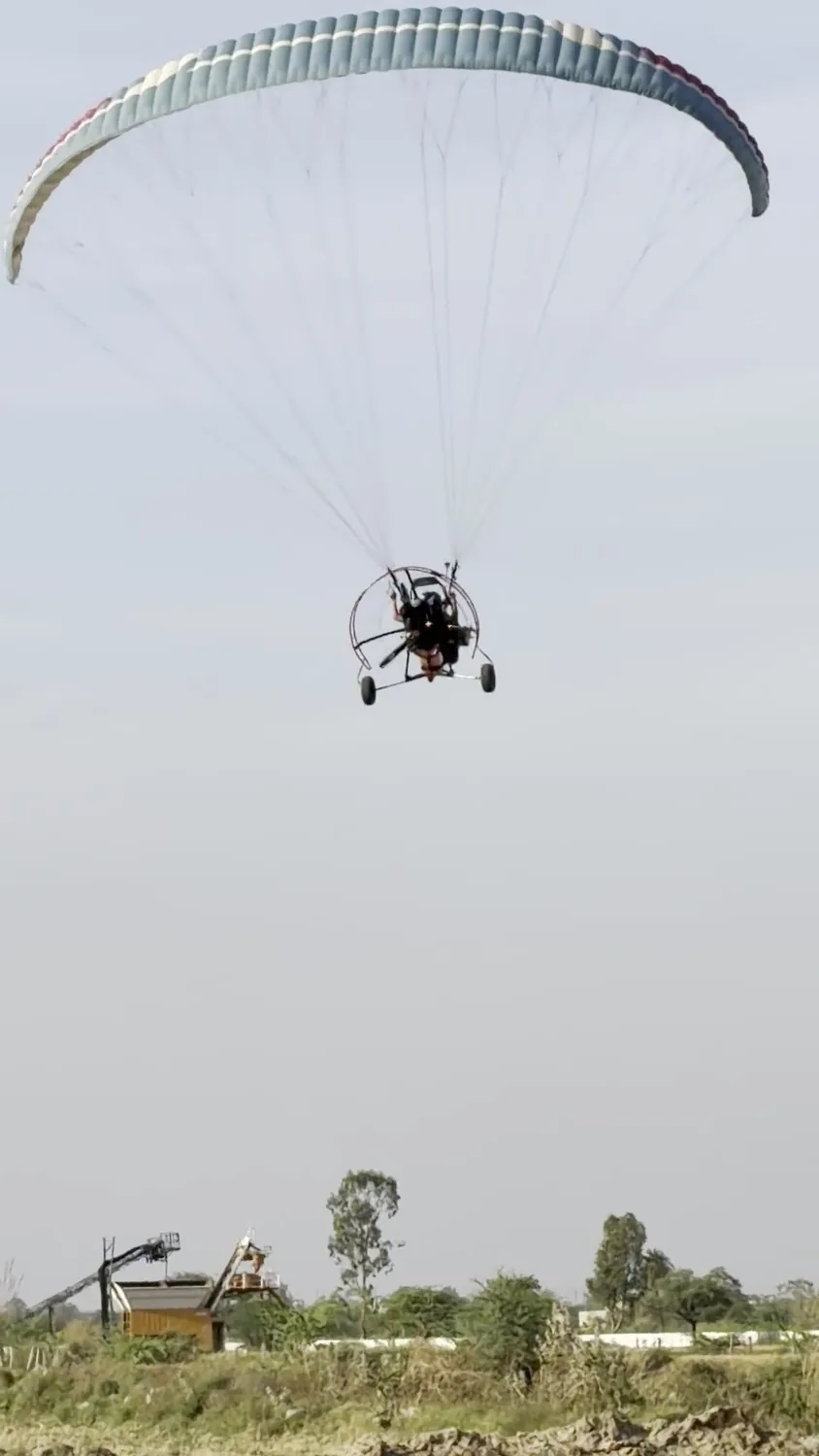 Motor paragliding trike flying above the field