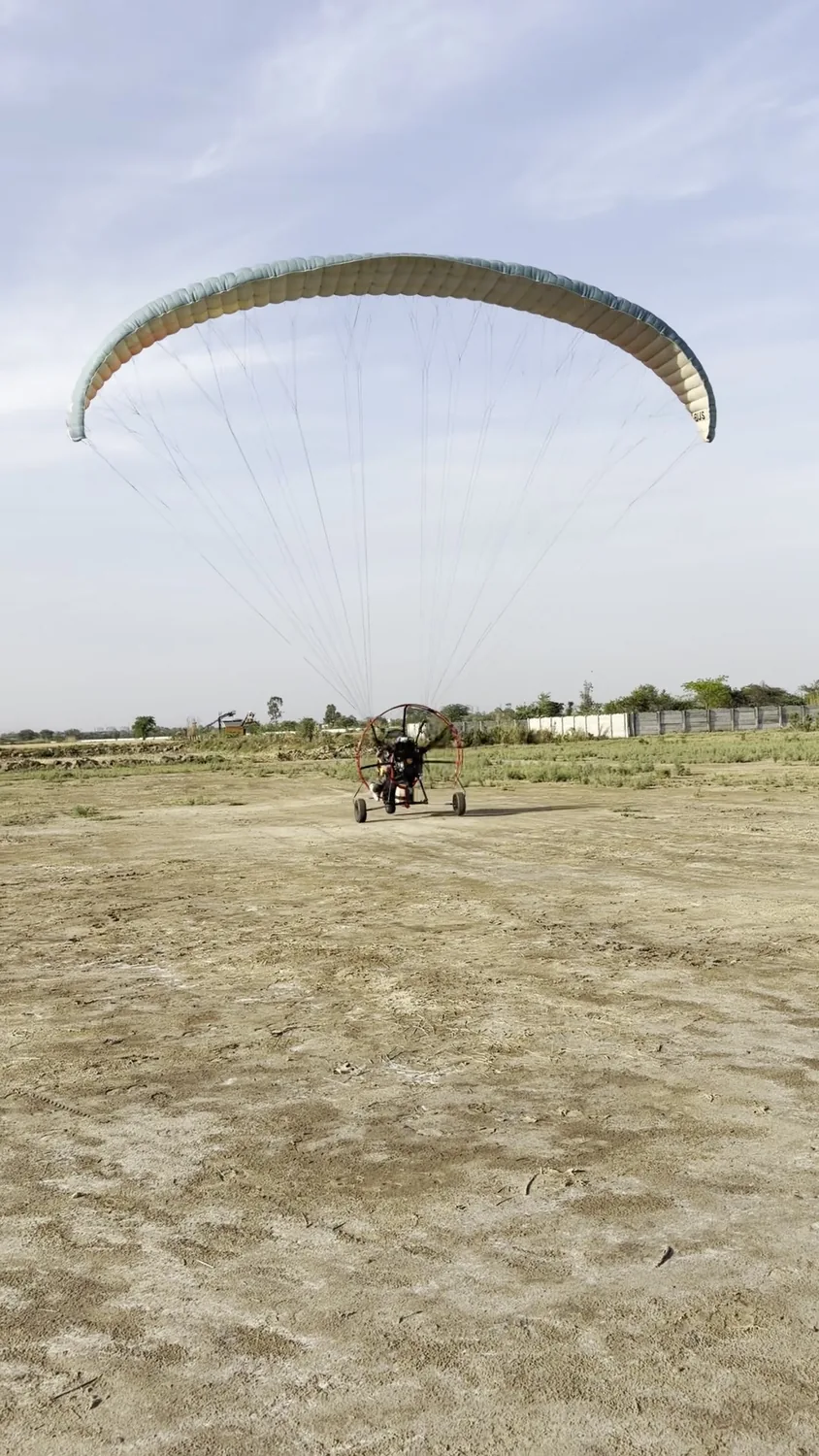 Canopy opening behind a motor paragliding trike on the field