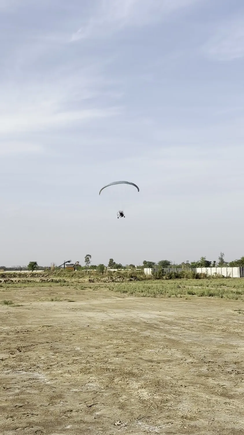 Motor paragliding flight viewed from a distance over the field